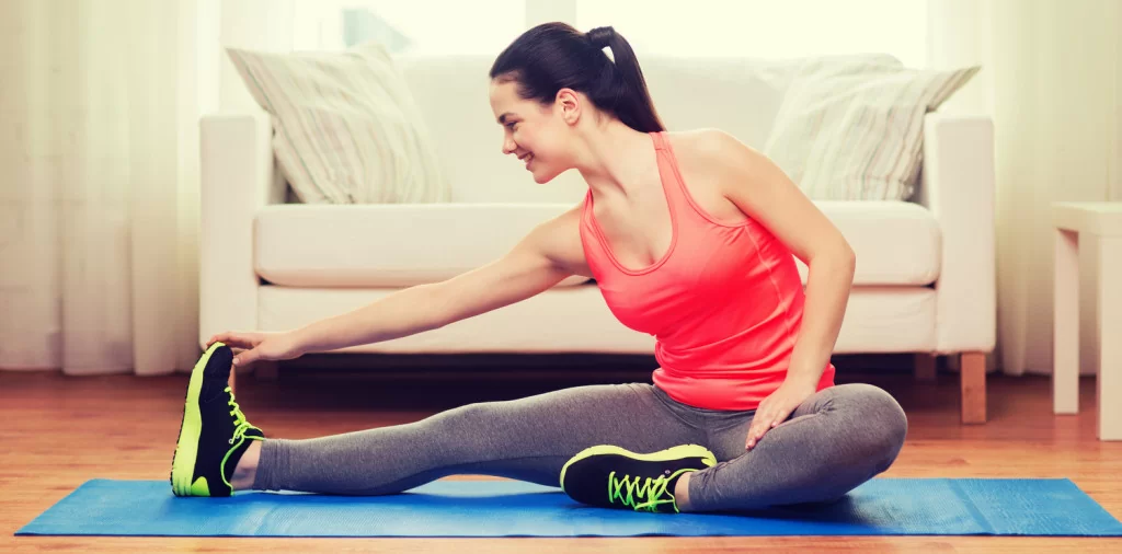 smiling teenage girl streching on floor at home